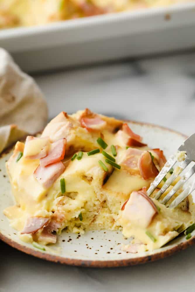 Taking a bite of egg benedict casserole topped with hollandaise sauce.