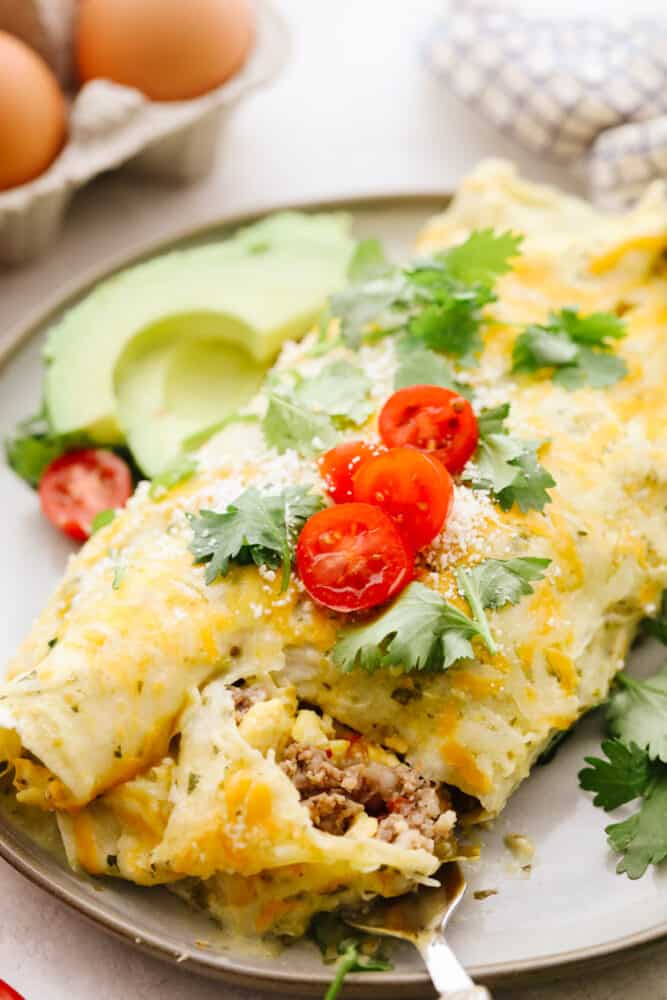 A close up of a breakfast enchilada with a fork cutting into it. 