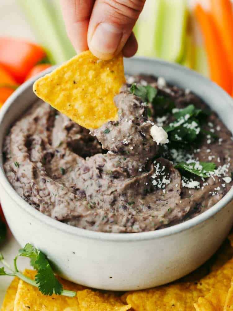 Dipping a chip into a bowl of bean dip.