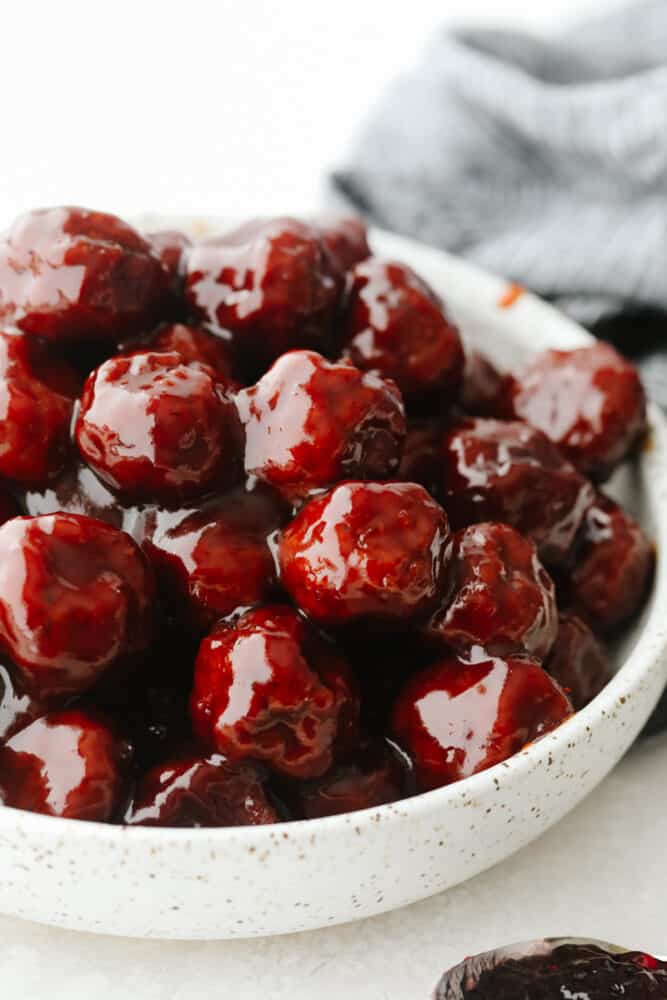 A white bowl filled with grape jelly meatballs. 
