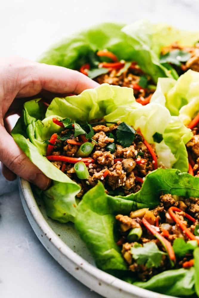 Asian lettuce wraps with a hand picking one up. 