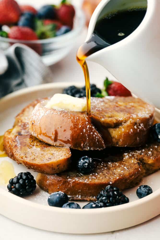 Challah French toast with maple syrup being over it. 