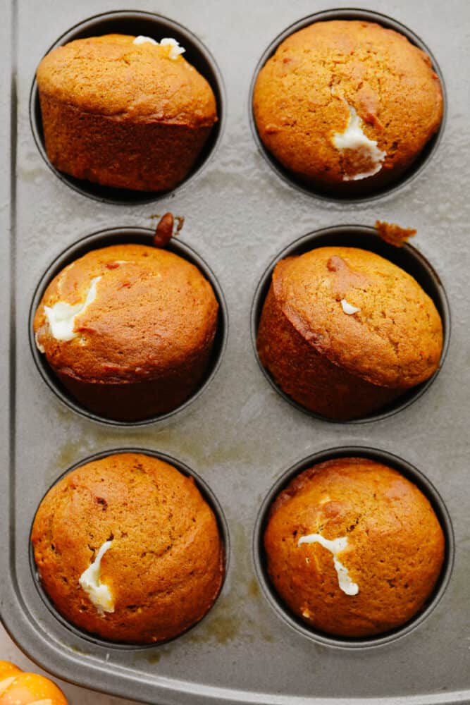 Pumpkin cream cheese muffins in a muffin tin. 