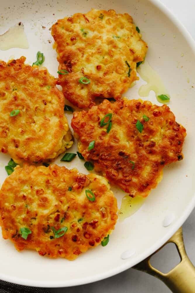 Corn fritters on a plate garnished with green onions.