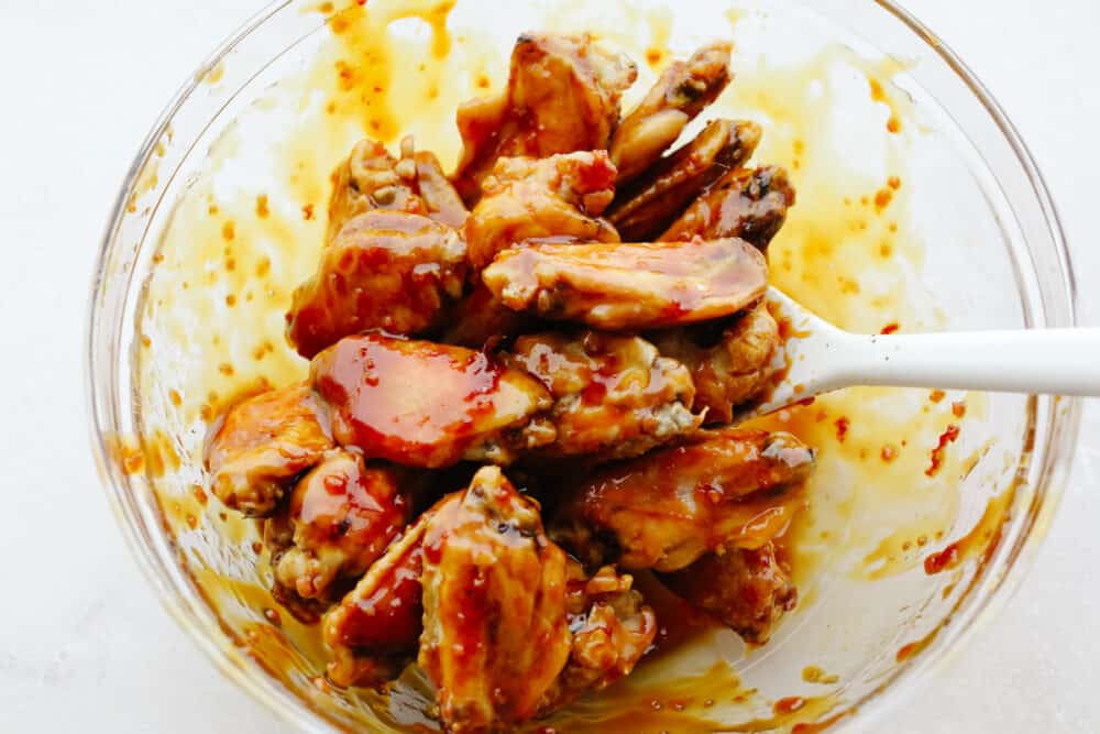 Buffalo wings being mixed with sauce. 