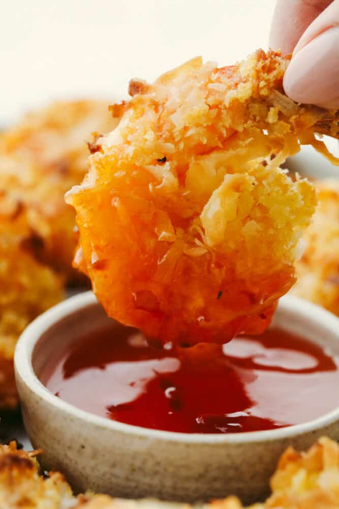 Baked Coconut Shrimp being dipped in sauce. 