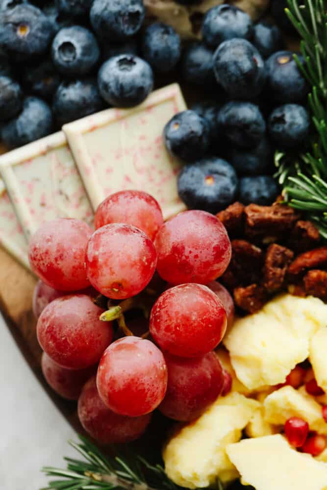 A close up of some grapes and fruit on the charcuterie board. 