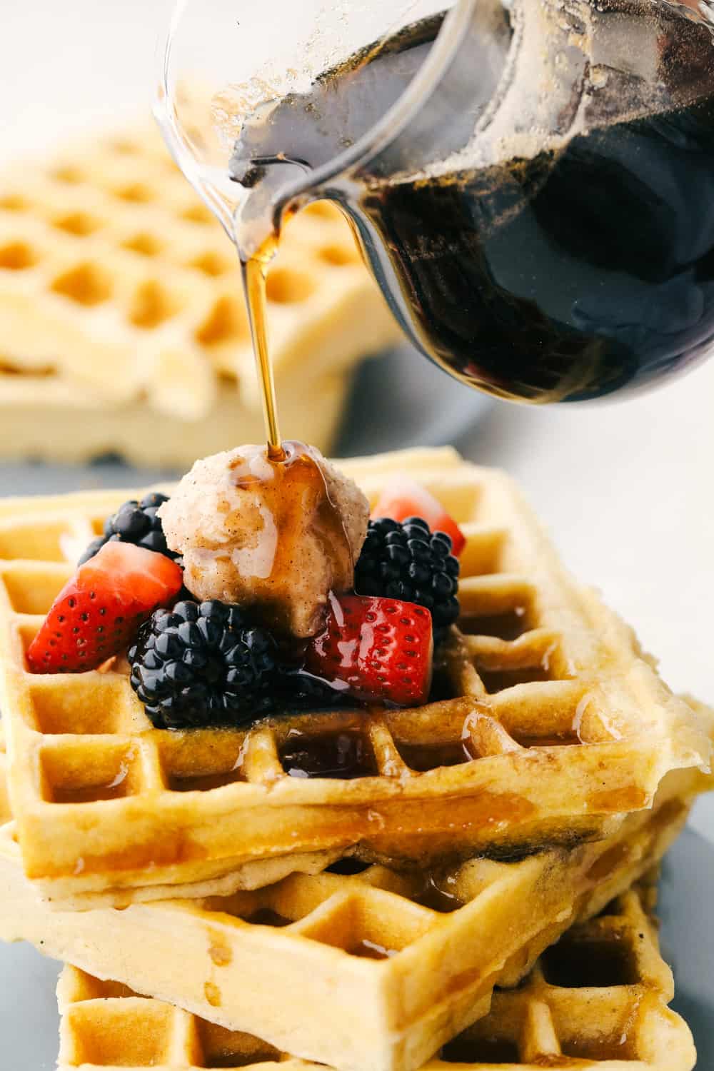 Pouring maple syrup over waffles. 