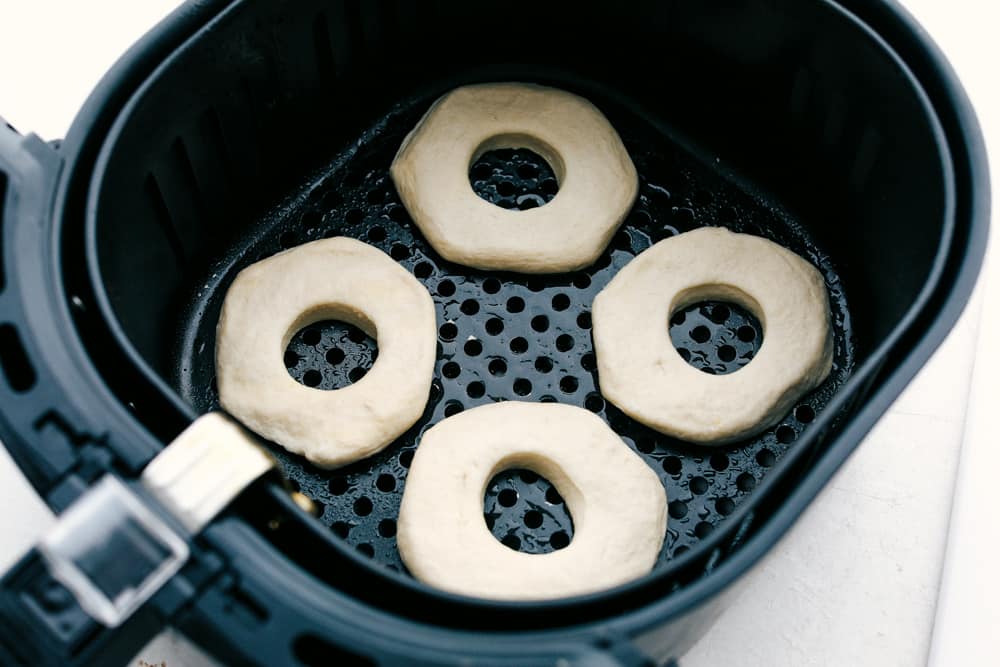 Biscuit donuts in an air fryer basket ready to bake. 