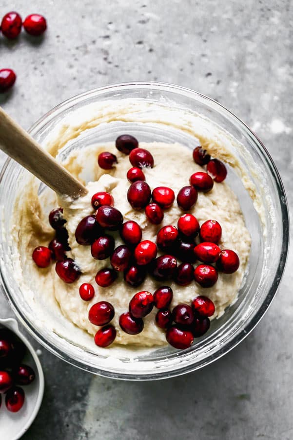 Muffin batter in a glass bowl with cranberries on top. 