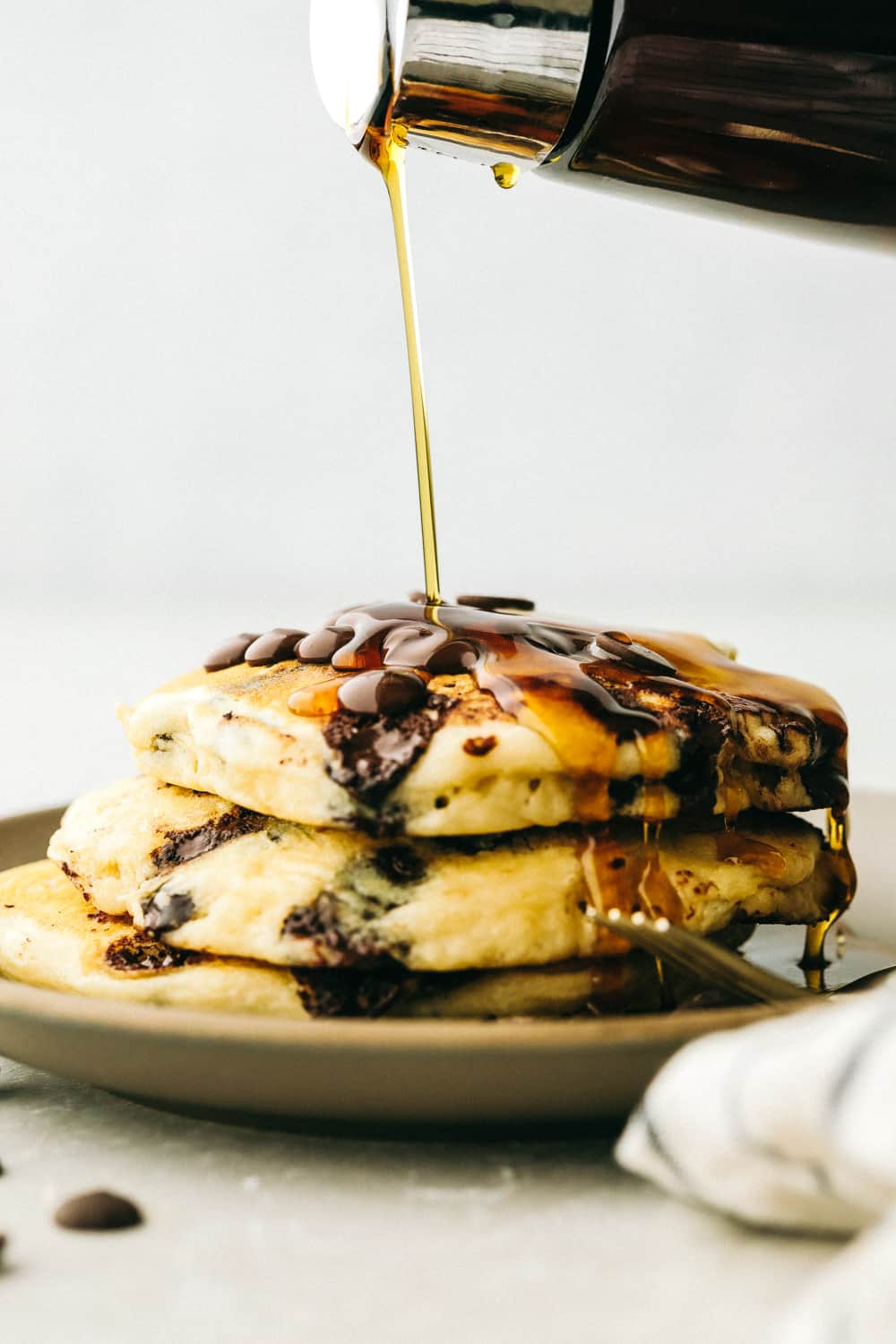 Syrup pouring on top of chocolate chip panckaes.