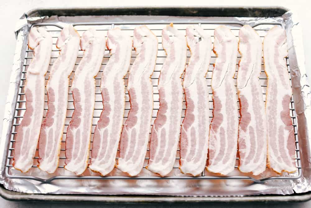 Raw Bacon on a lined cookie sheet getting ready to Bake