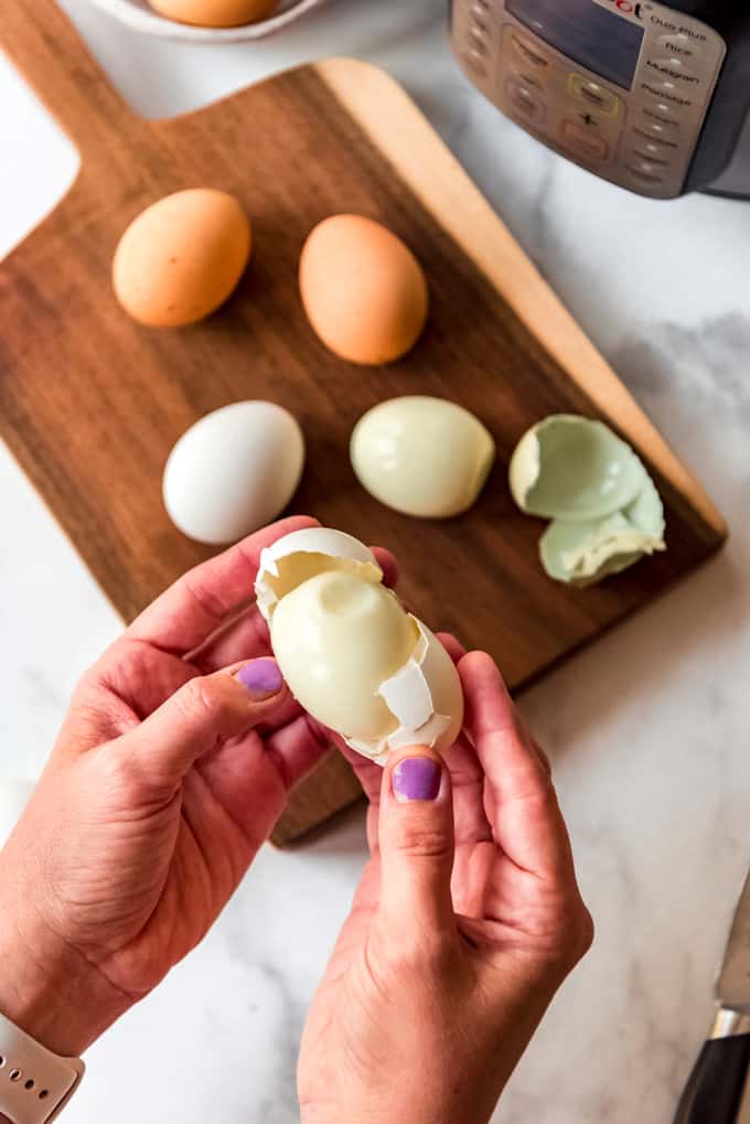 Hands holding a peeled hard boiled egg.