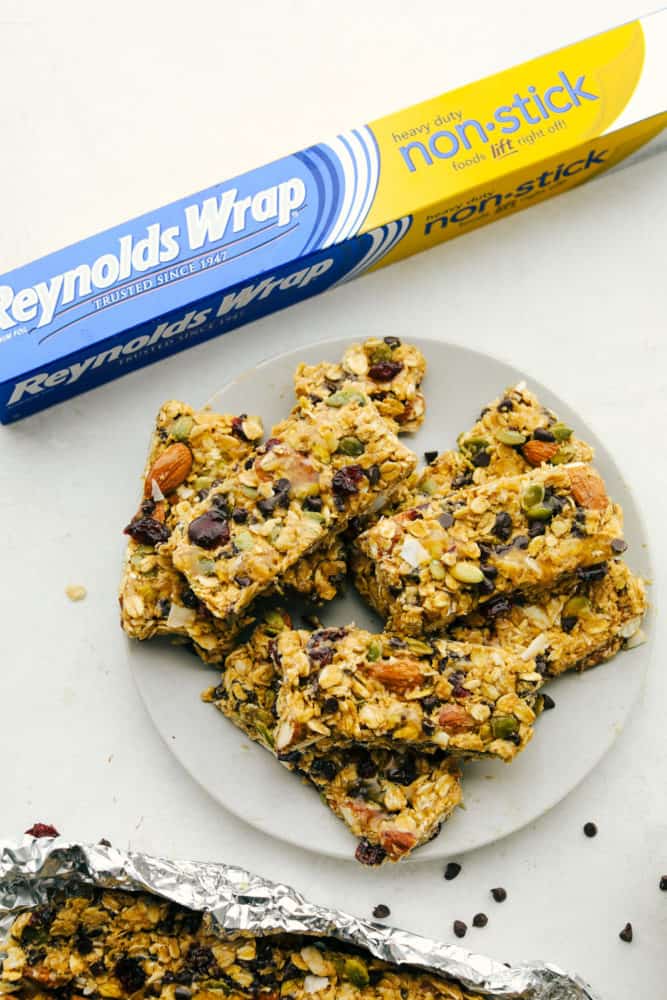 Granola bars stacked on top of each other on a plate with the nonstick wrapper in the photo. 
