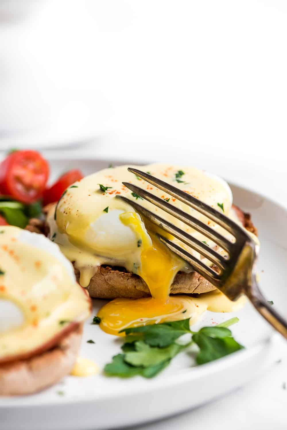 Egg Benedict on a plate being cut into with a fork.