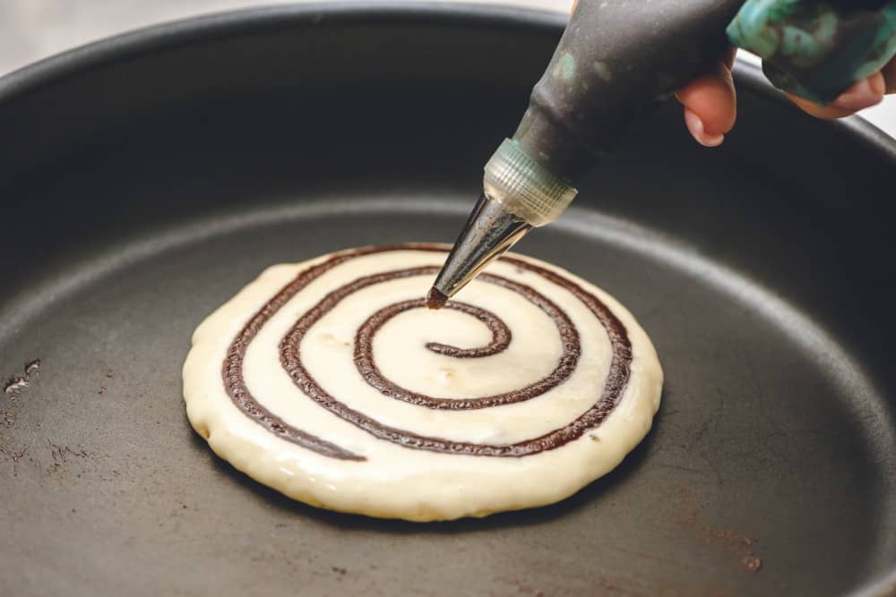 Cinnamon roll pancakes being cooked on the stove top.