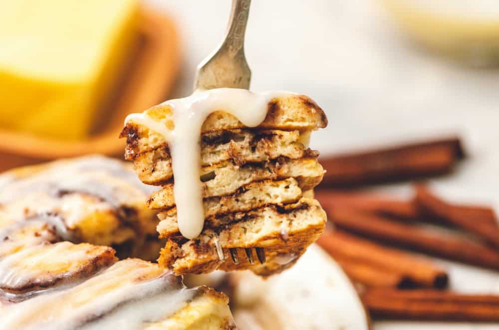 Cinnamon roll pancakes layered on top of each other with the cream cheese glaze. 
