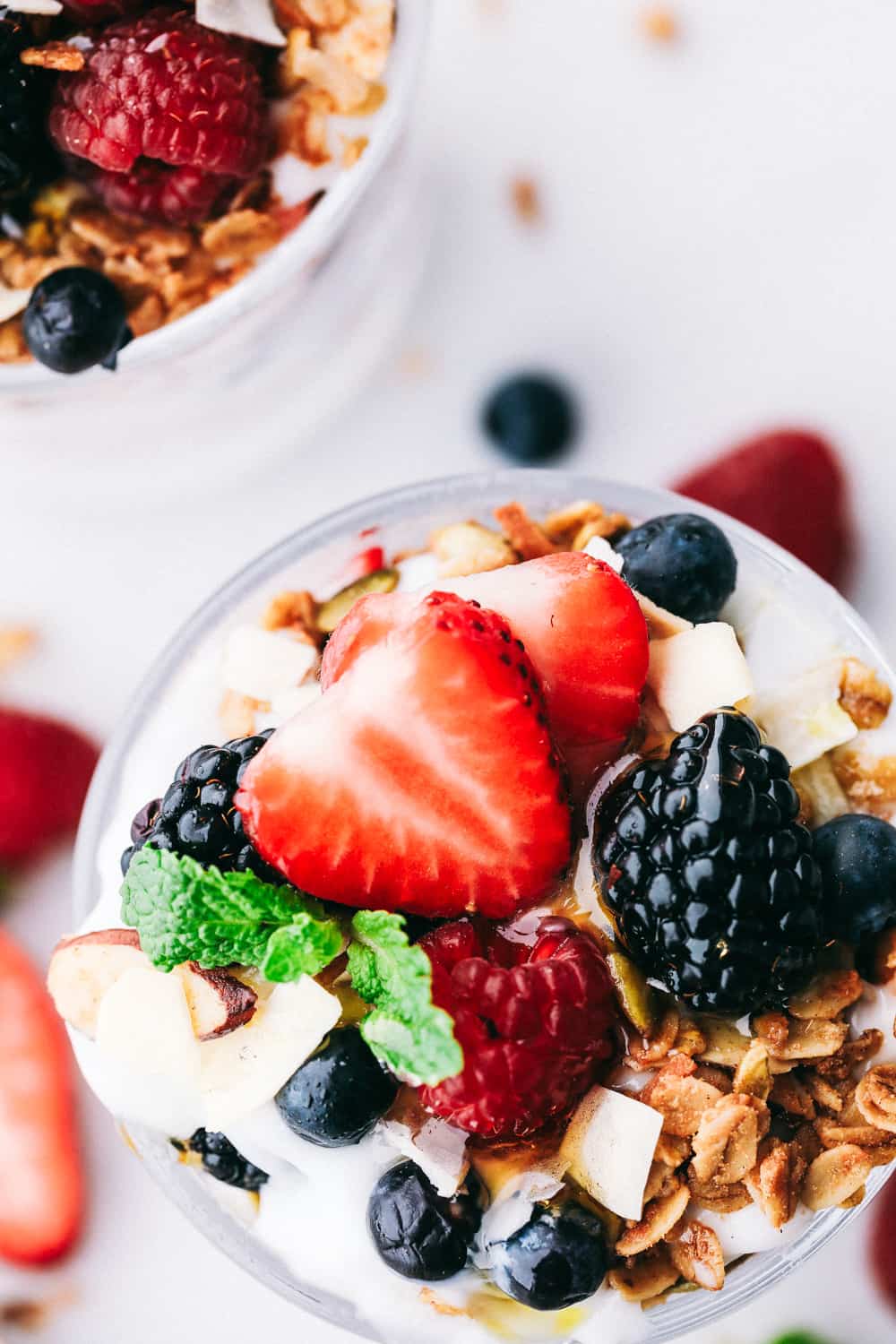 Yogurt parfait topped with fresh strawberries, blackberries, raspberries and blueberries with granola garnished on top.