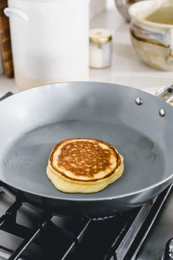 Keto pancake cooking on a skillet over the gas stove top.