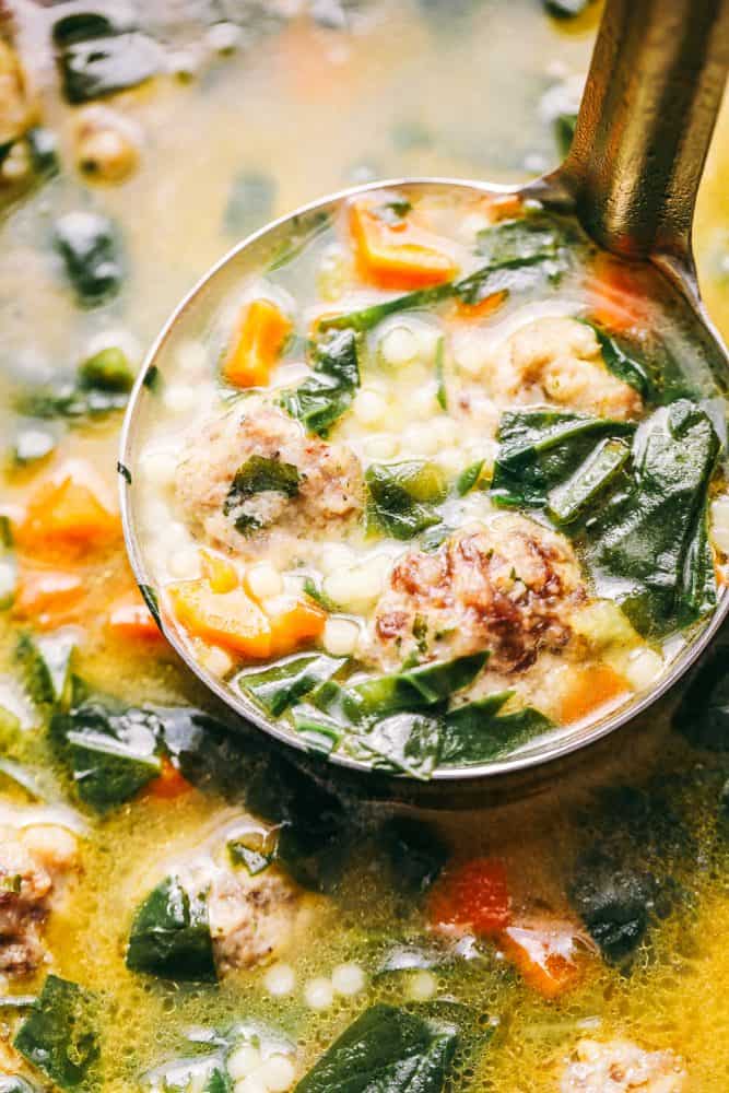 Close up of Italian wedding soup in a bowl with a full ladle.