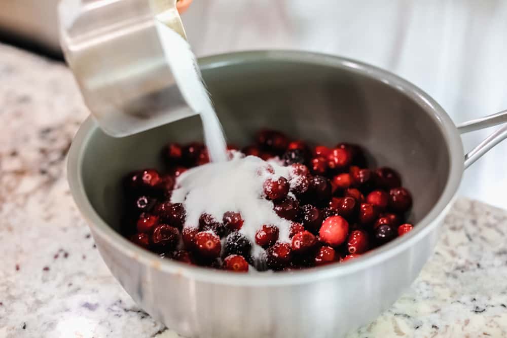 Sugar being poured onto cranberries. 