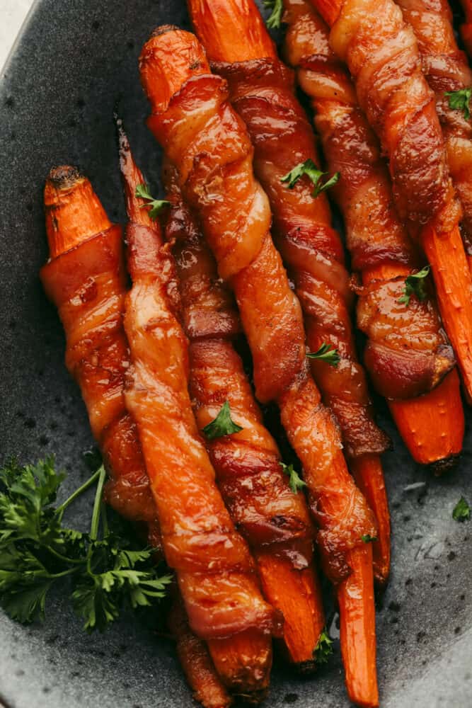 Baked bacon-wrapped carrots garnished with parsley.