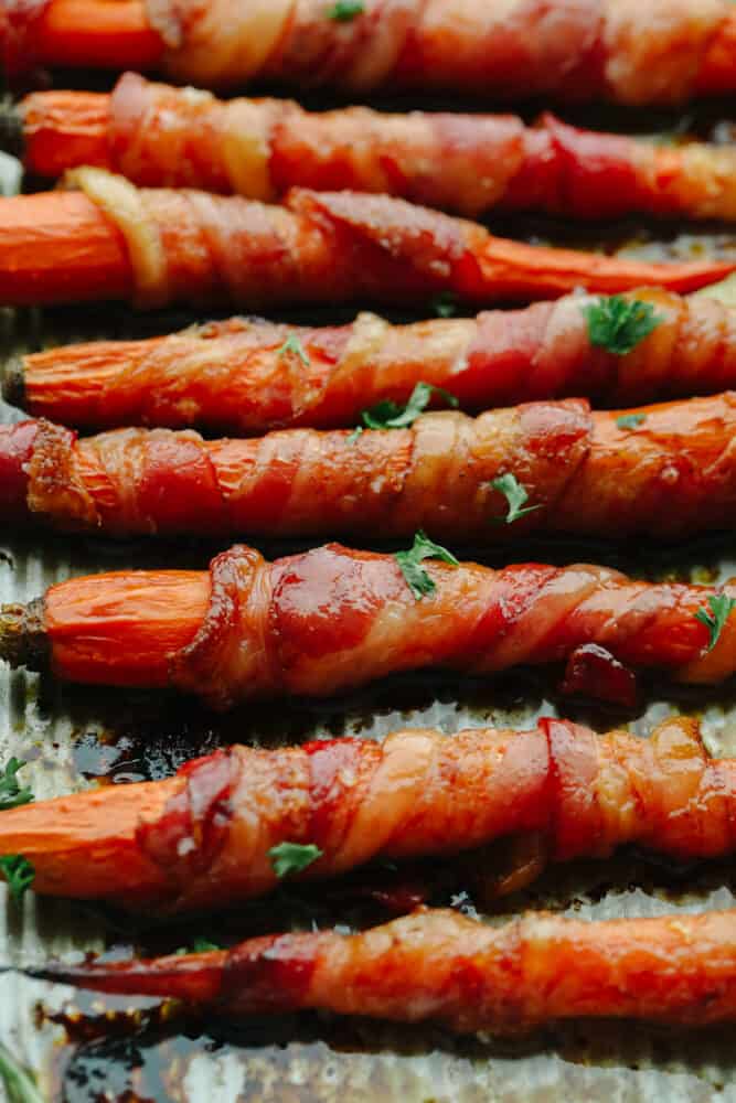 Closeup of bacon-wrapped, honey-glazed carrots garnished with parsley.