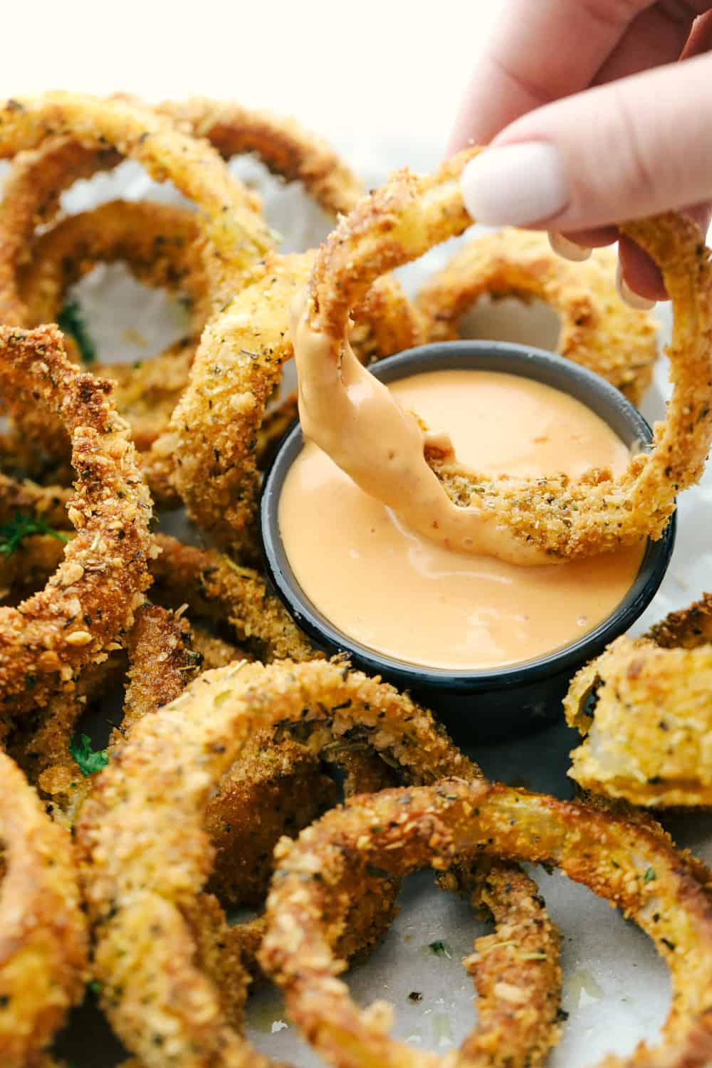 Dipping onion rings in dipping sauce for eating. 
