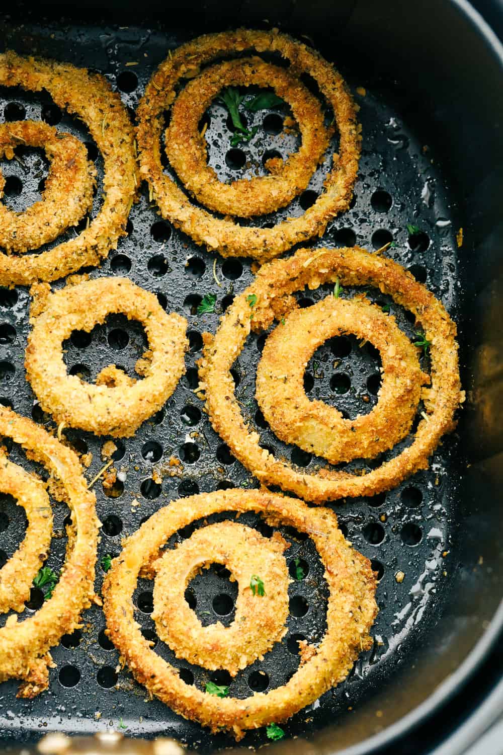Air fryer onion rings in the air fryer basket. 