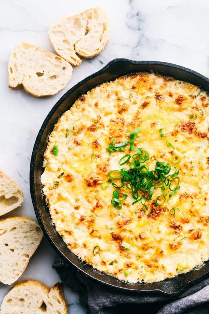 Hot Crab Dip in a metal pan with sliced bread on the side. 