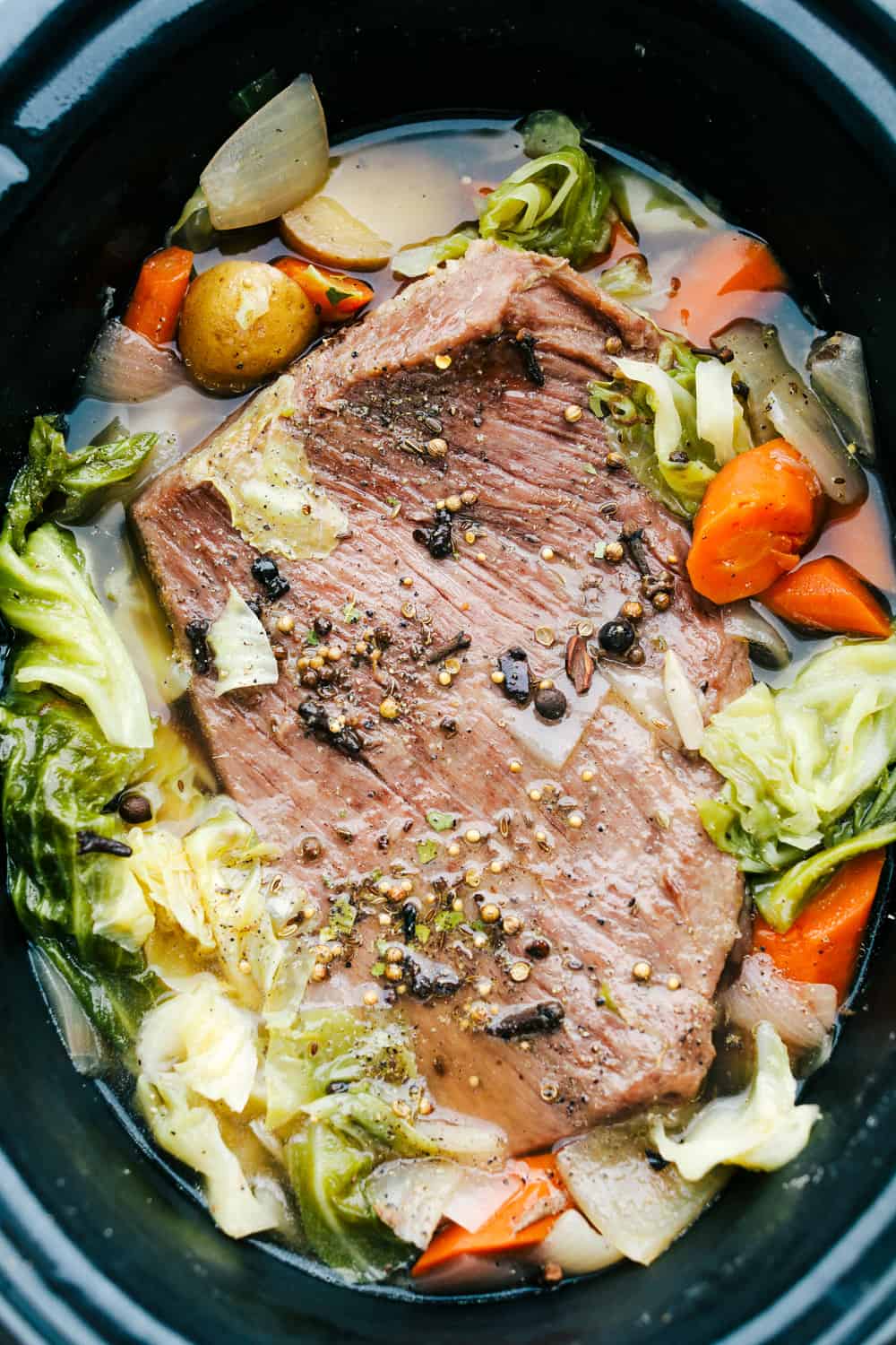 Corn beef in a slow cooker with cabbage and chopped up carrots and potatoes. 