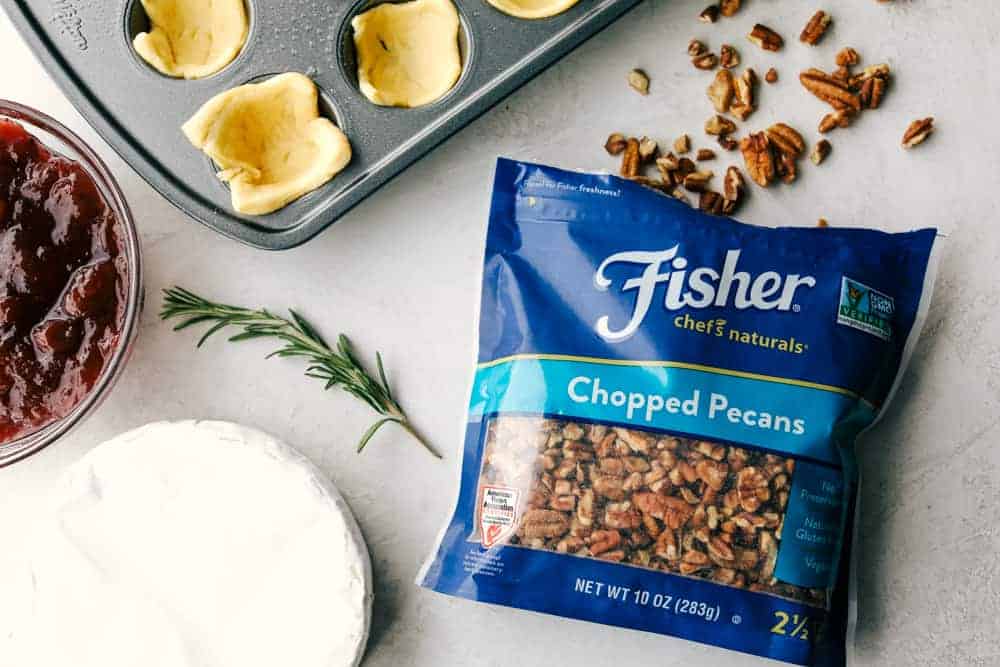 Fisher pecans in a bag next to brie, cranberry sauce and crescent rolls. 