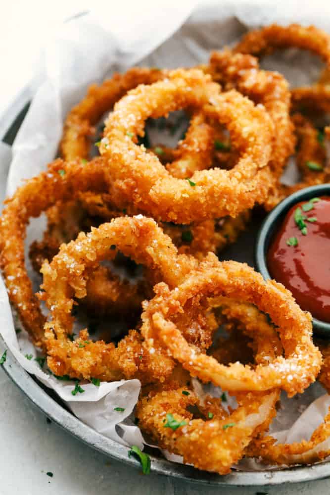 Finished onion rings on a plate with dipping sauce.