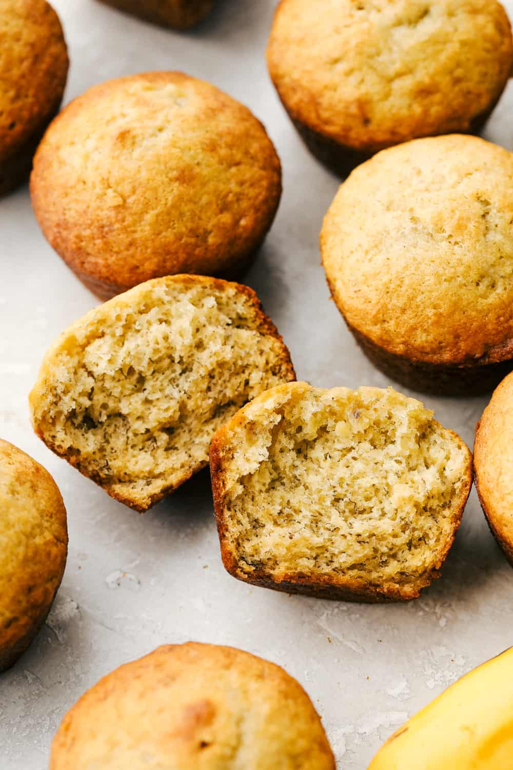 Banana muffins in a bunch with one cut open to show texture. 