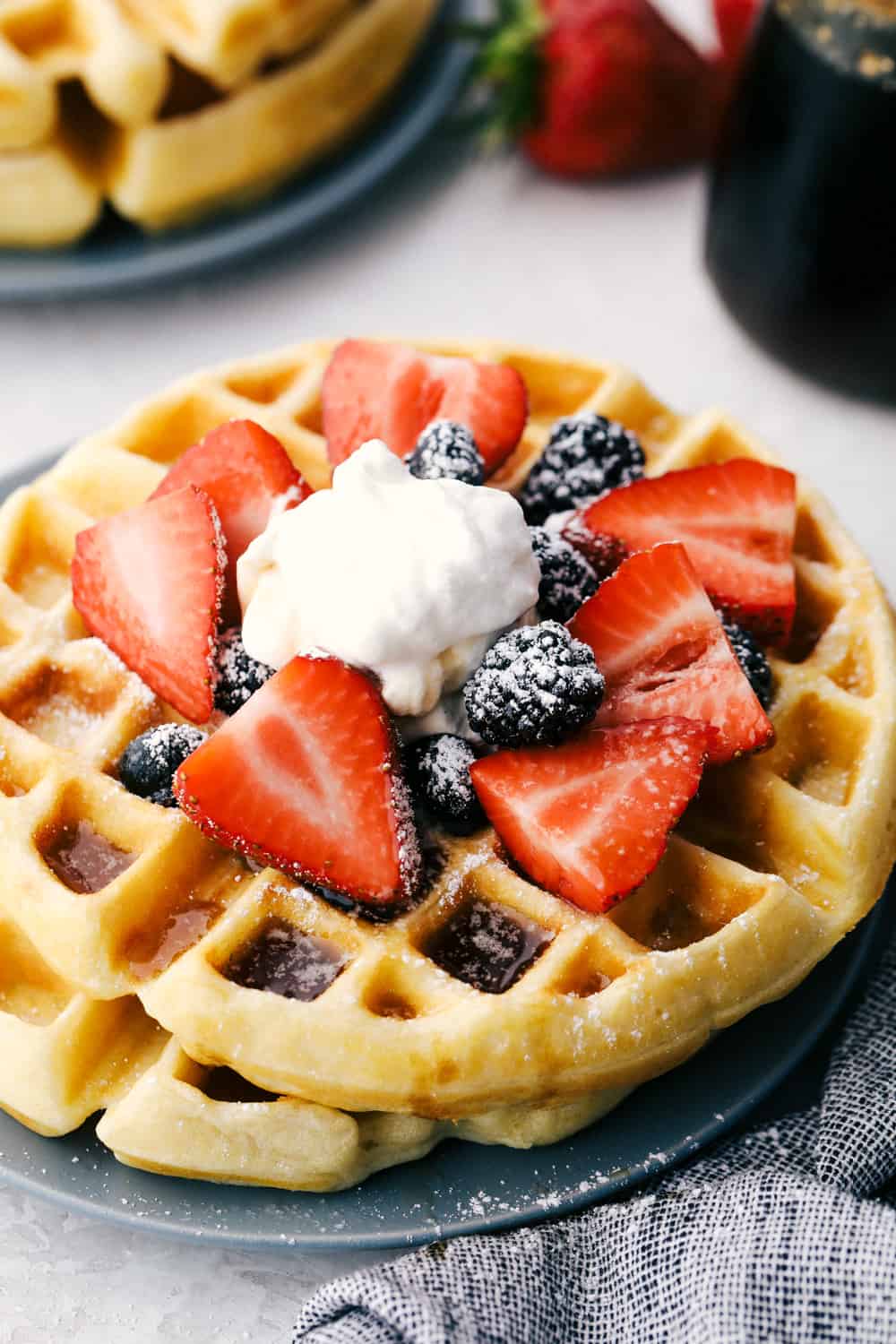 Stacked belgian waffles with berries and cream. 