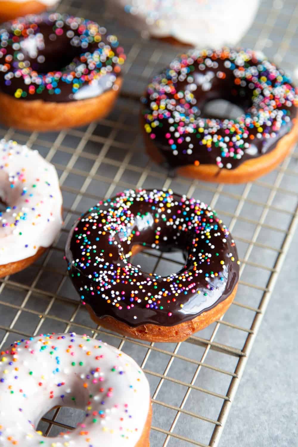 Glazed donuts with sprinkles on a wire rack.