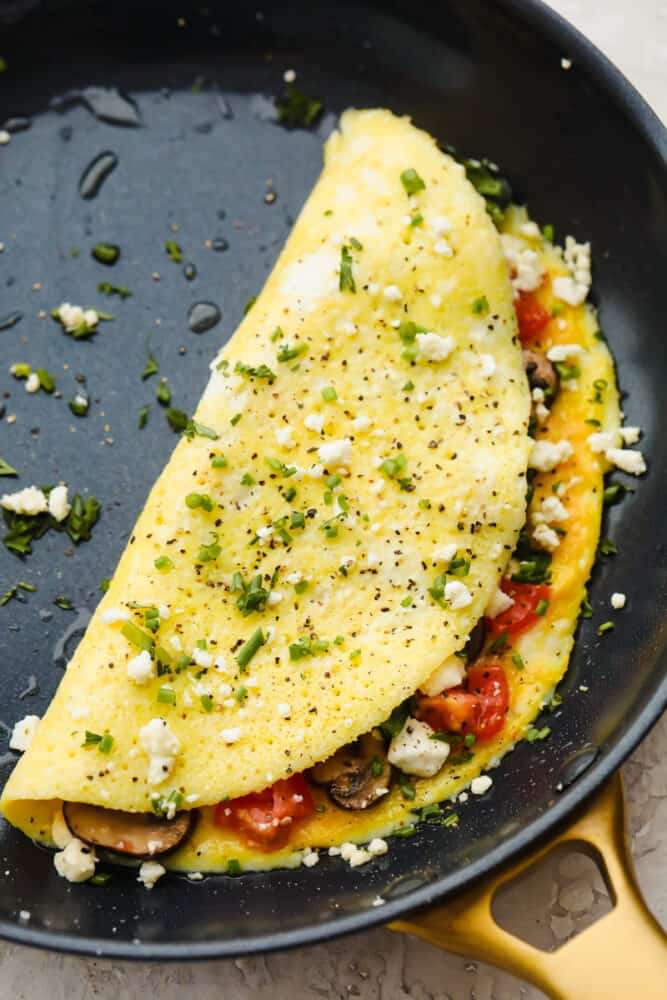 A cooked omelet with toppings in a pan. 