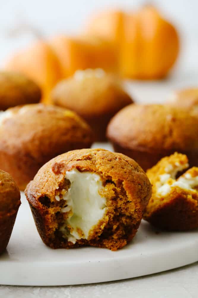 Pumpkin muffin cut in half showing cream cheese in the middle. 