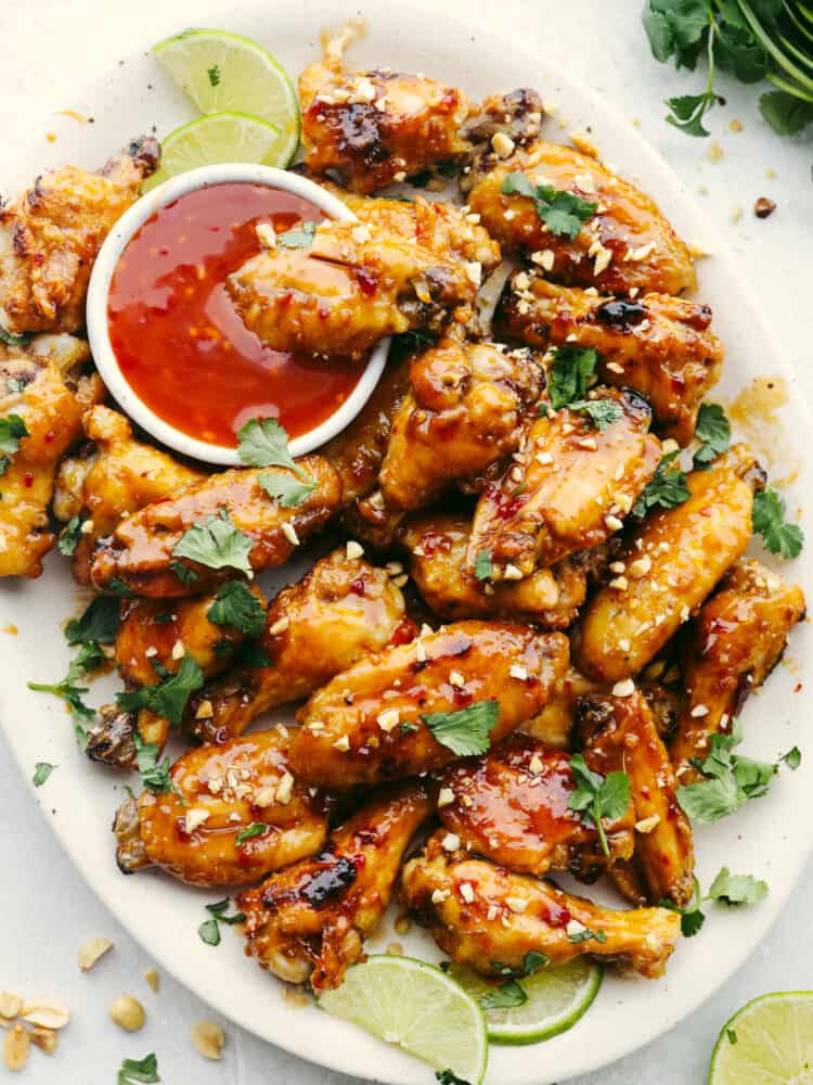 A platter of wings with a small bowl of Thai sauce. 