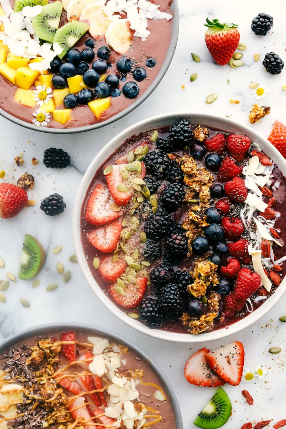 Three Acai Bowls with three different flavoring and toppings of fruit and granola. 