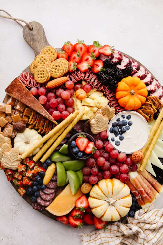 A fall charcuterie board filled with fruits, cheese, meat and crackers. 