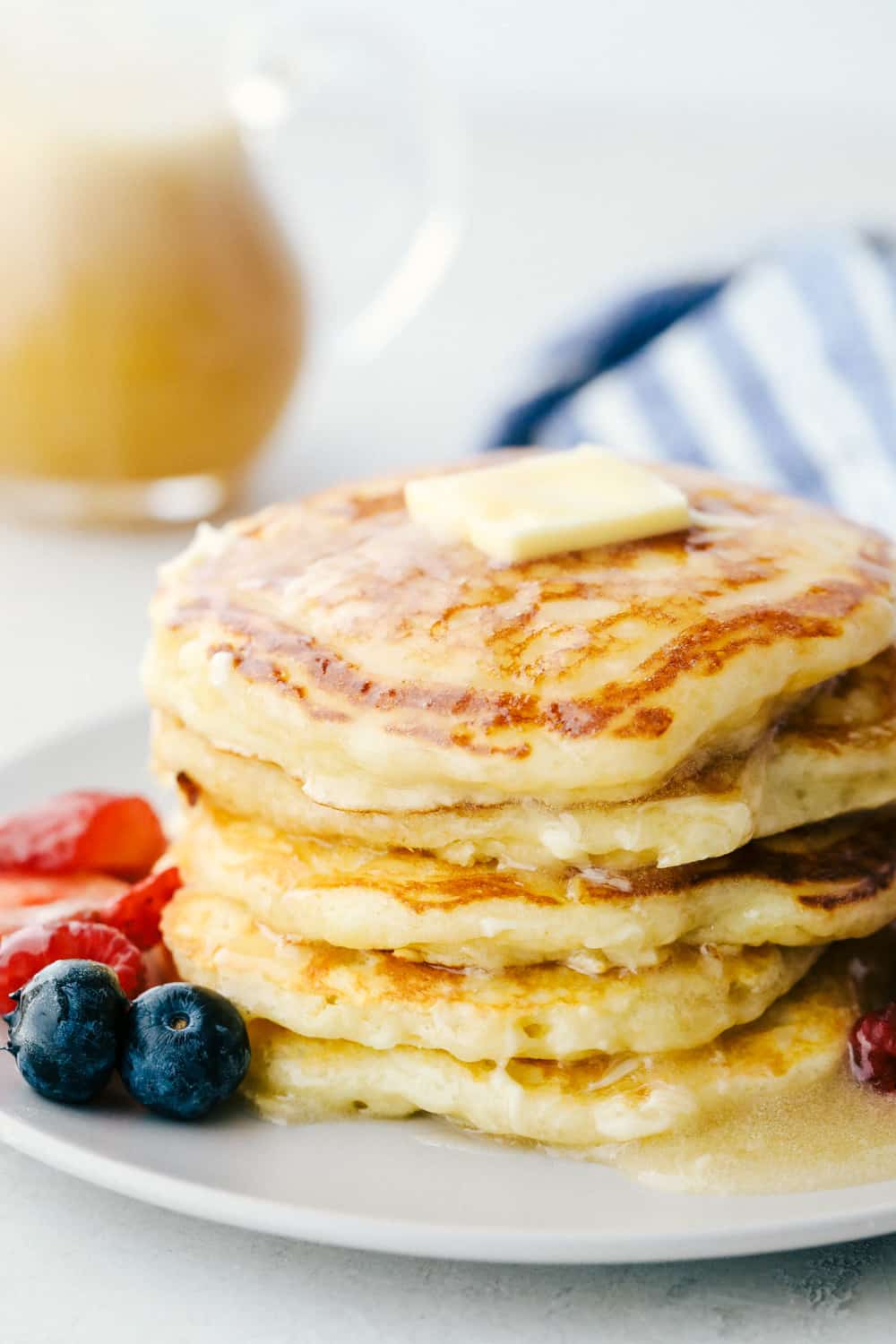 Fluffy Buttermilk pancakes on a plate with butter and syrup.