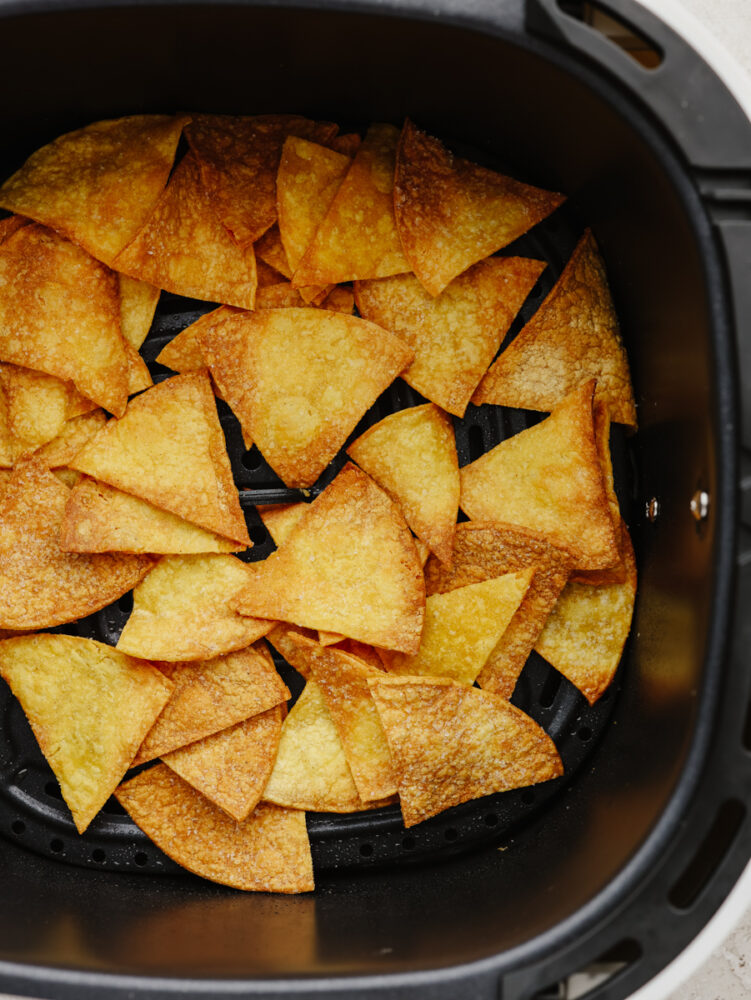 Homemade tortilla chips in the basket of an air fryer.