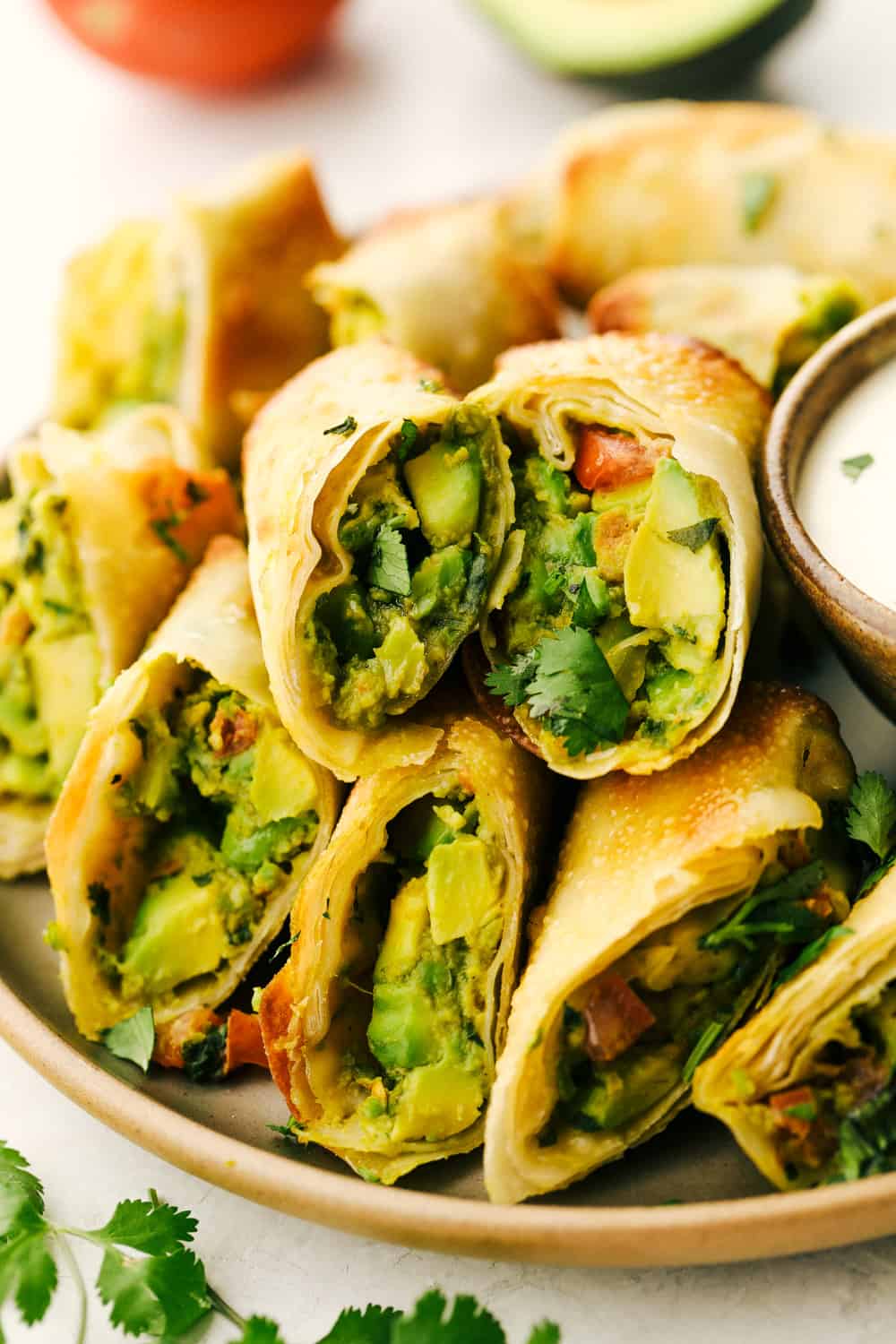 Avocado egg rolls split and layered on a plate. 