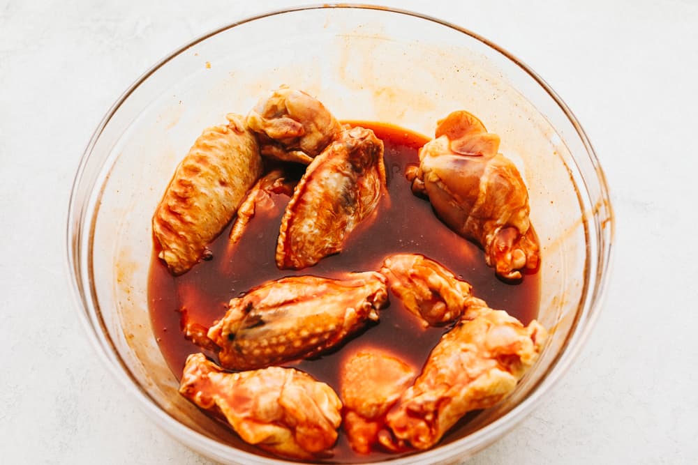 Marinating chicken wings in a clear bowl.