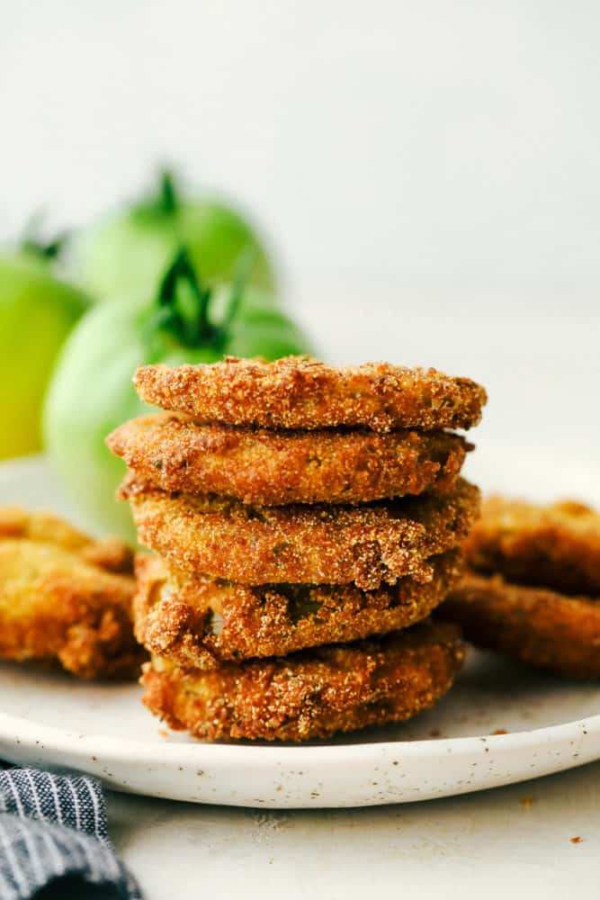 Stack of fried green tomatoes on a white plate.